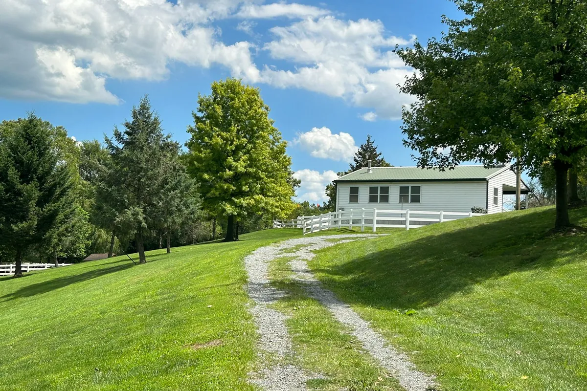 A gravel path running up a mowed lawn to a white outbuilding, with no pavers or edging