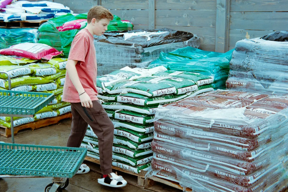 A shopper walking past pallets of bagged topsoil, potting mix and mulch at a garden center